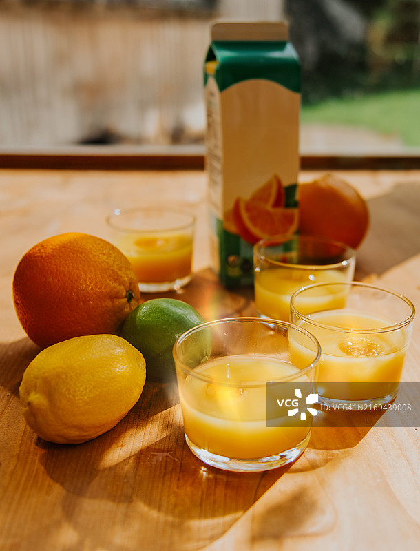阳光明媚的早晨，木桌上的橘汁和新鲜柑橘汁图片素材