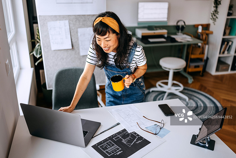 身着休闲装的女商人居家办公，手持咖啡杯图片素材