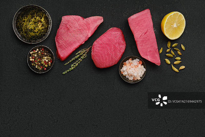 黑色背景上的新鲜生金枪鱼排和香料俯视图图片素材