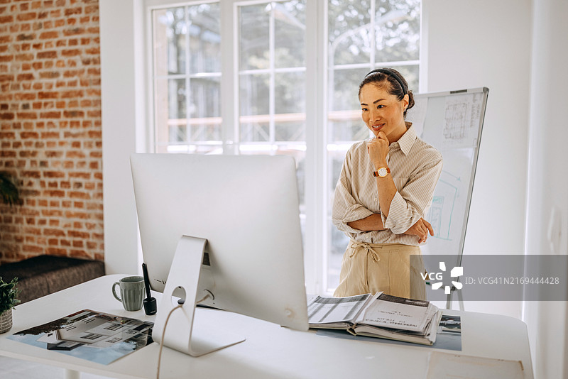 在现代办公室使用台式电脑的微笑美丽休闲装扮女人图片素材