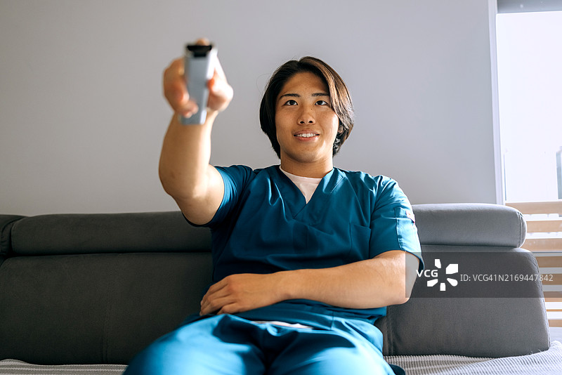 年轻男护士在家沙发上看电视图片素材