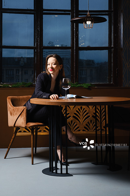 快乐的女人在酒吧里喝着葡萄酒，看着最喜欢的杂志图片素材