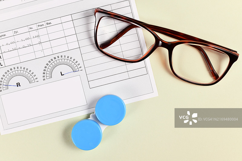 黄色背景上的医疗眼镜处方、眼镜和隐形眼镜盒图片素材