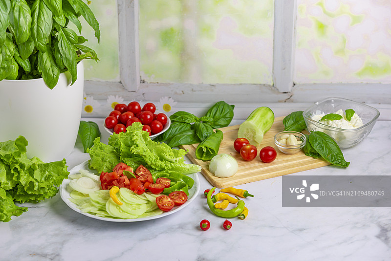 木板和盘子上的新鲜蔬菜、沙拉配料：黄瓜、西红柿、生菜、罗勒、意大利椒、洋葱、大蒜、辣椒图片素材