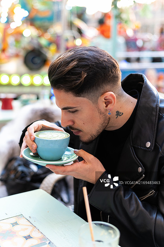 年轻男人与朋友在早午餐期间品尝抹茶拿铁图片素材