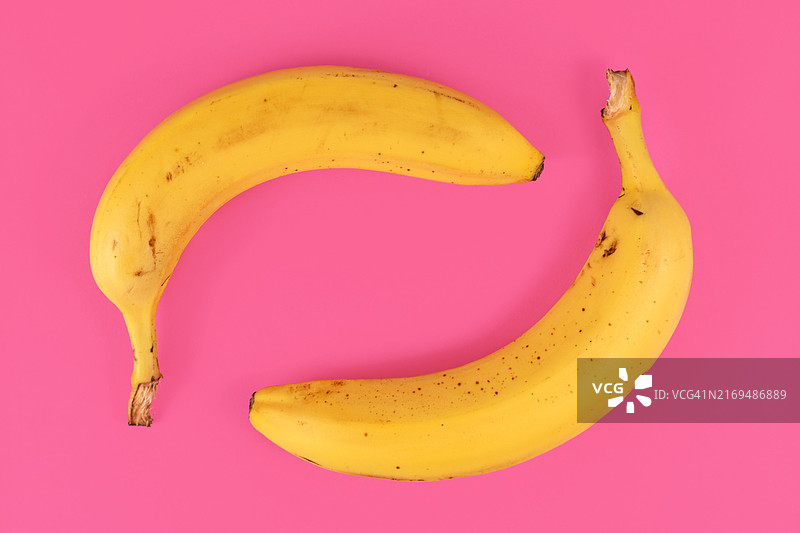 粉色背景上的两个带皮成熟香蕉图片素材