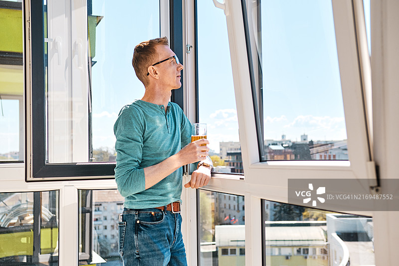 戴眼镜的中年男人站在高层建筑的阳台上图片素材