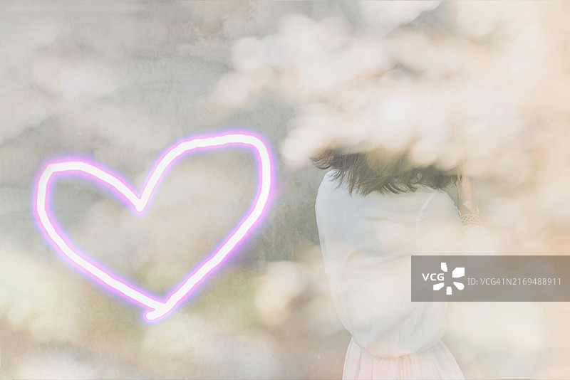 在柔和的模糊倒影、粉红色霓虹灯心的背景下，穿着浅色衬衫的女人的模糊身影的后视图图片素材