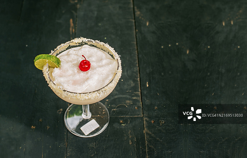 木桌上的椰子玛格丽特鸡尾酒与樱桃装饰图片素材
