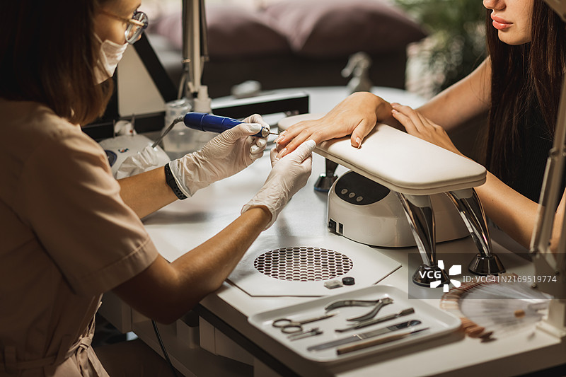 美甲师用设备为女性双手打磨指甲图片素材