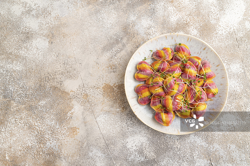 棕色背景的彩色饺子配胡椒和香草图片素材