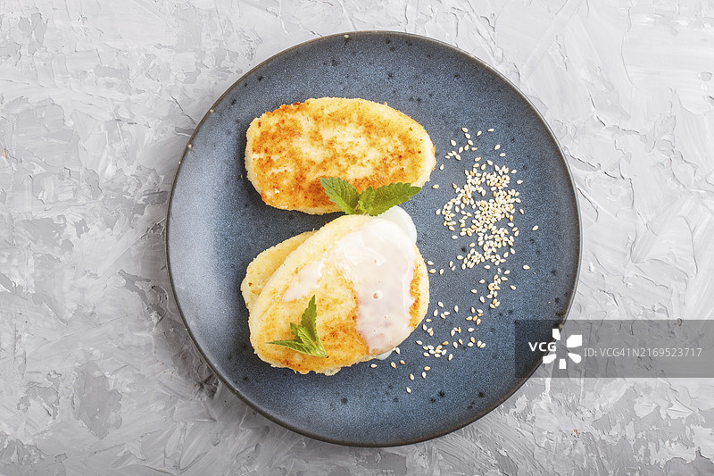 灰色混凝土背景上，蓝色陶瓷盘中的奶酪薄饼配牛奶酱，俯视图片素材