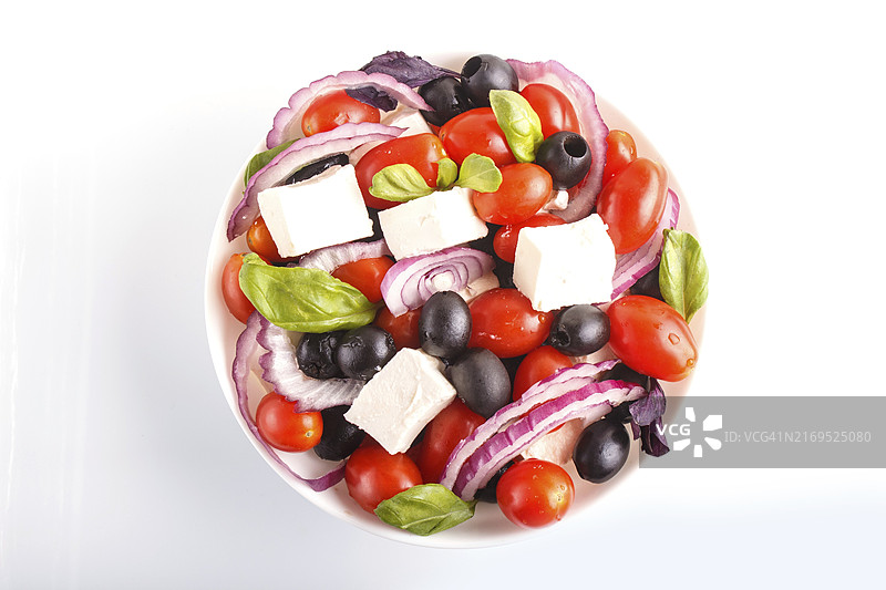 白色背景上含有新鲜圣女果、菲达奶酪、黑橄榄、罗勒和洋葱的希腊沙拉，顶视图图片素材