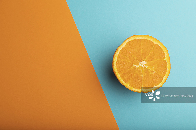 橙色和蓝色柔和背景上的成熟橙子切片，顶部视角，扁平风格图片素材