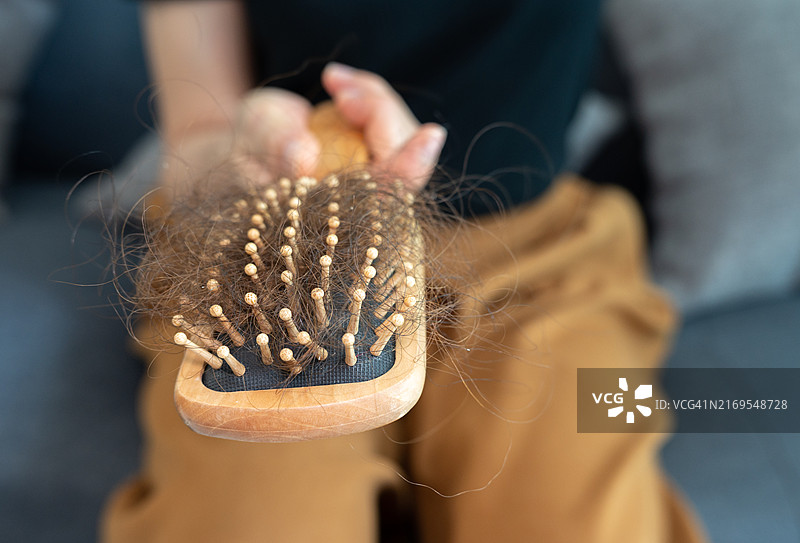 女子梳头后手持梳子，头发凌乱脱落图片素材