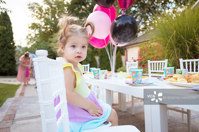 坐在生日派对桌旁的一岁女孩图片素材