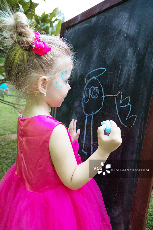 在黑板上绘画的金发小女孩图片素材