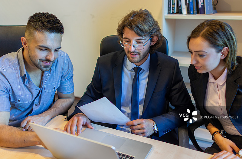 一小群人围坐在笔记本电脑旁讨论销售策略图片素材