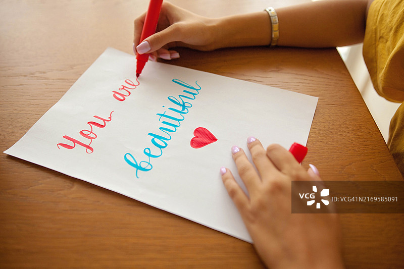 每一次笔触都充满力量和自爱，年轻女孩的手写着“你很美丽”的标语图片素材