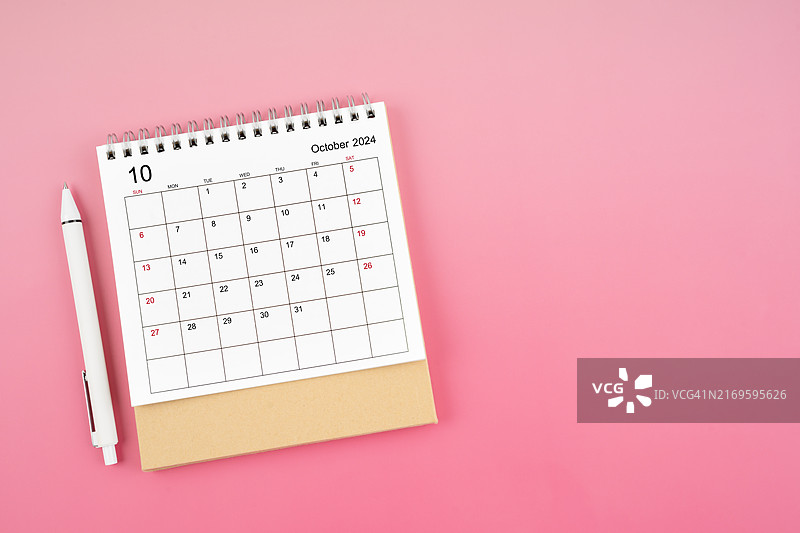 2024年10月粉色背景上的台历和笔，带复制空间图片素材