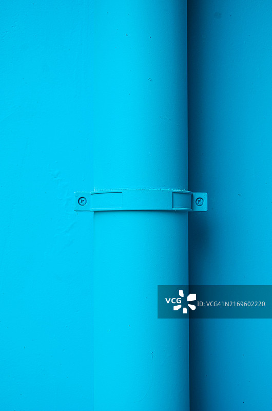 连接在蓝色墙壁上的排水管道图片素材