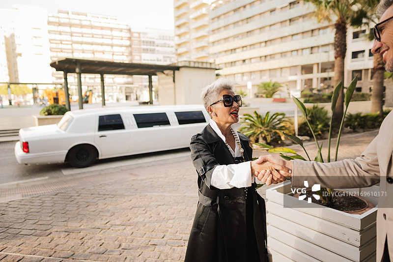 在酒店外豪华轿车前与商人握手的年长女商人图片素材