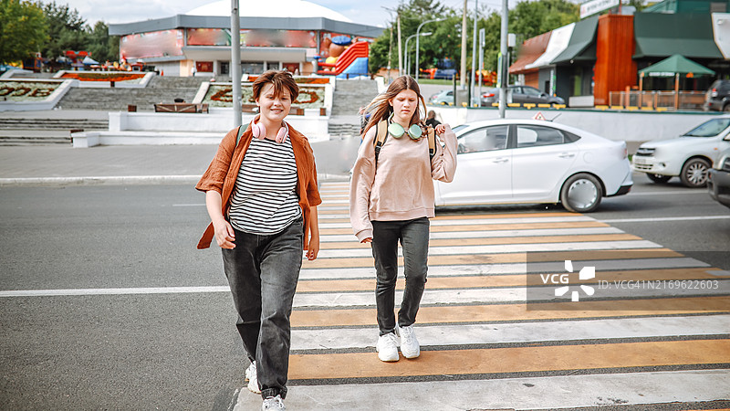 两个少年走在人行横道上，享受城市探险，共度美好时光图片素材
