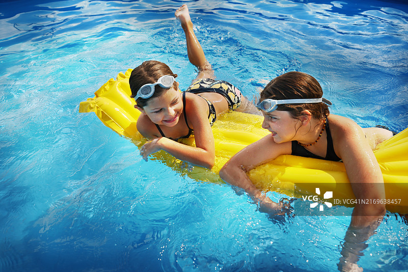 晴天泳池中躺在充气浮具上的女孩图片素材