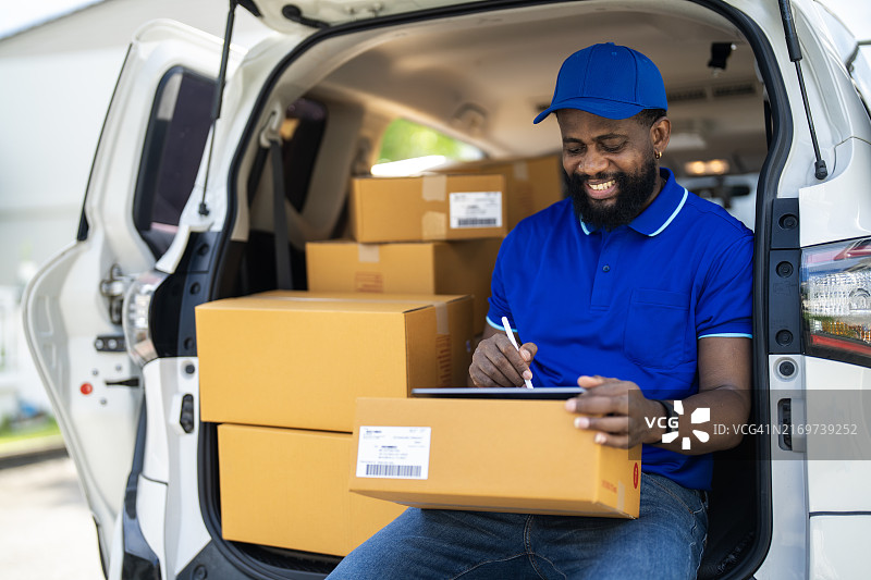 快乐的年轻送货员抱着纸箱图片素材