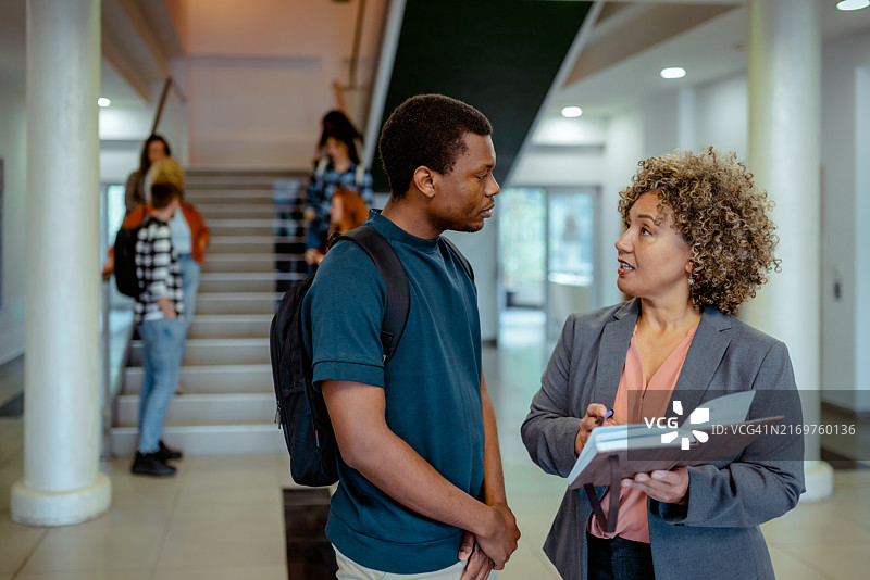 黑人男大学生和他的成熟的女教授在大学走廊上谈话图片素材