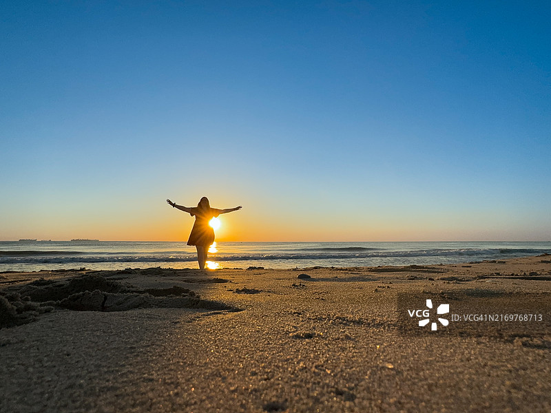 年轻女子在海滩享受日出图片素材