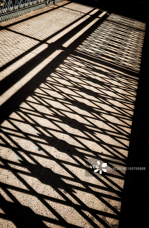 曼哈顿大桥人行道上铸铁栅栏投下的阴影，位于东河之上图片素材