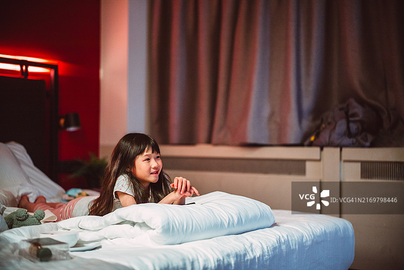 年轻快乐的女孩在舒适的酒店房间里看电视图片素材