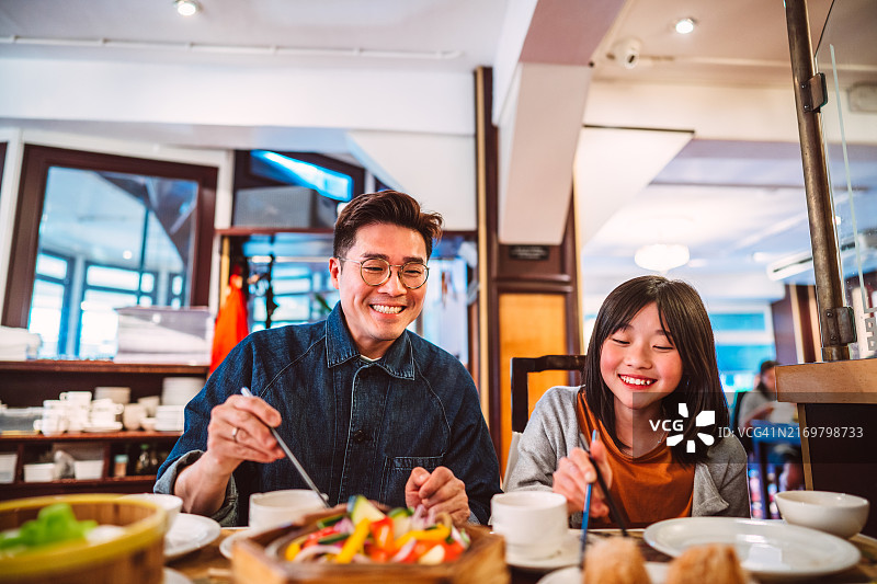 亚洲父女在新城市旅行时在中餐馆享用健康的纯素餐图片素材