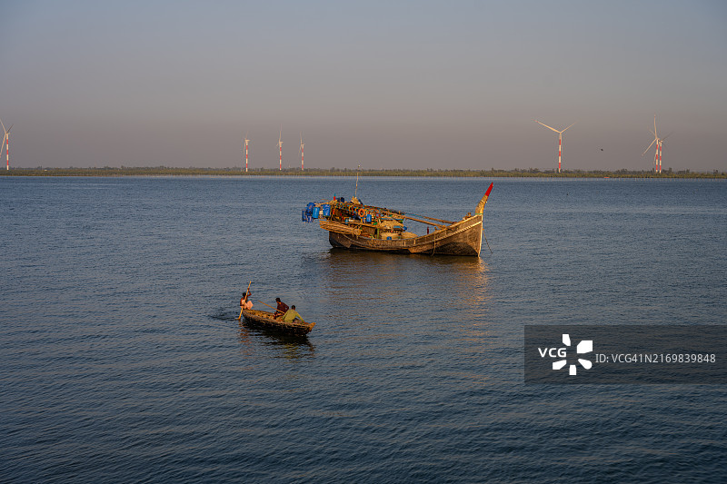 马赫什卡利岛的传统渔船与远处的风力涡轮机图片素材