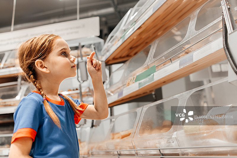 小学女生在面包店选择糕点图片素材