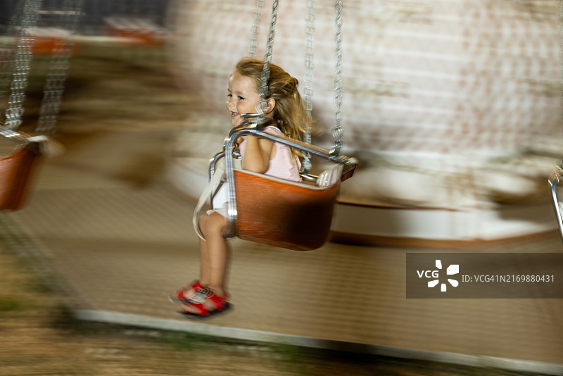 小女孩坐在旋转摇摆机上图片素材