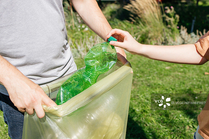 手持塑料瓶扔进垃圾袋特写图片素材