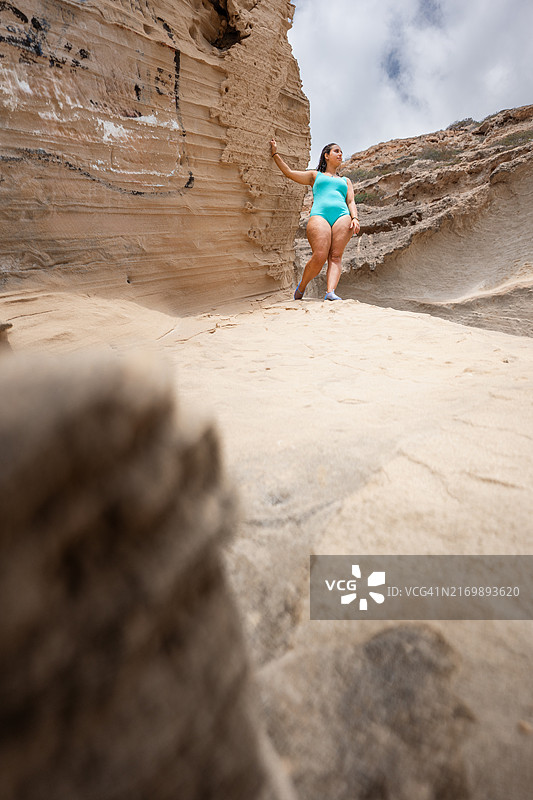 女子身穿绿松石泳衣站在沙漠峡谷中图片素材