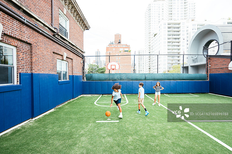 不同肤色的学生在城市户外球场打篮球图片素材