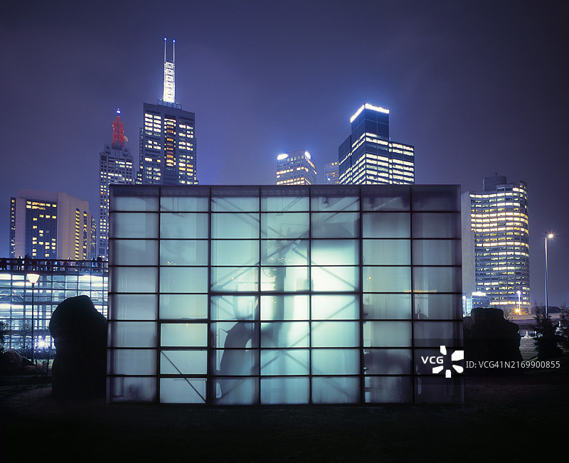 黄昏时分，灯火通明的城市天际线前的半透明泵站图片素材