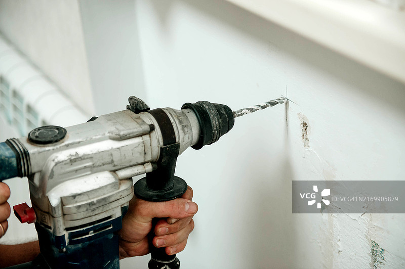 男人拿着锤钻在墙上钻孔图片素材