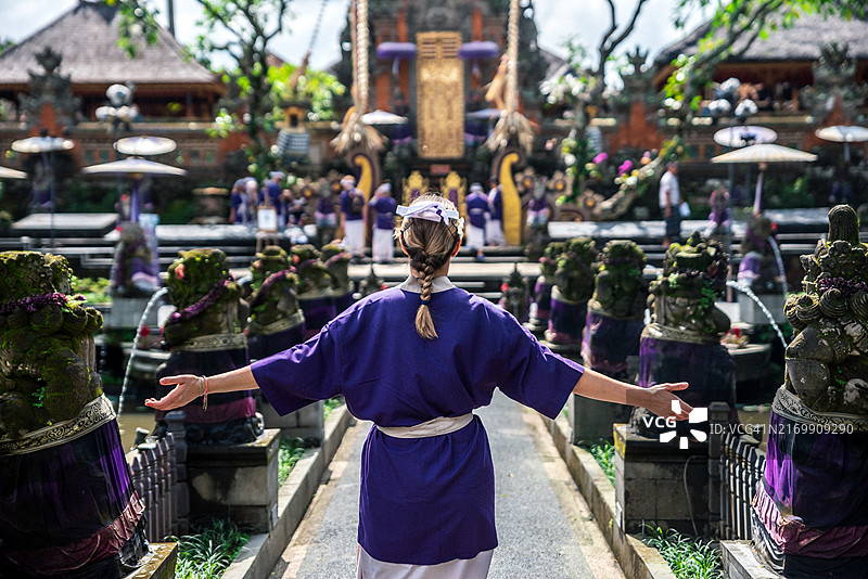 年轻女人身穿巴厘岛服装，张开双臂在普拉塔曼萨拉斯瓦蒂神庙周围行走图片素材