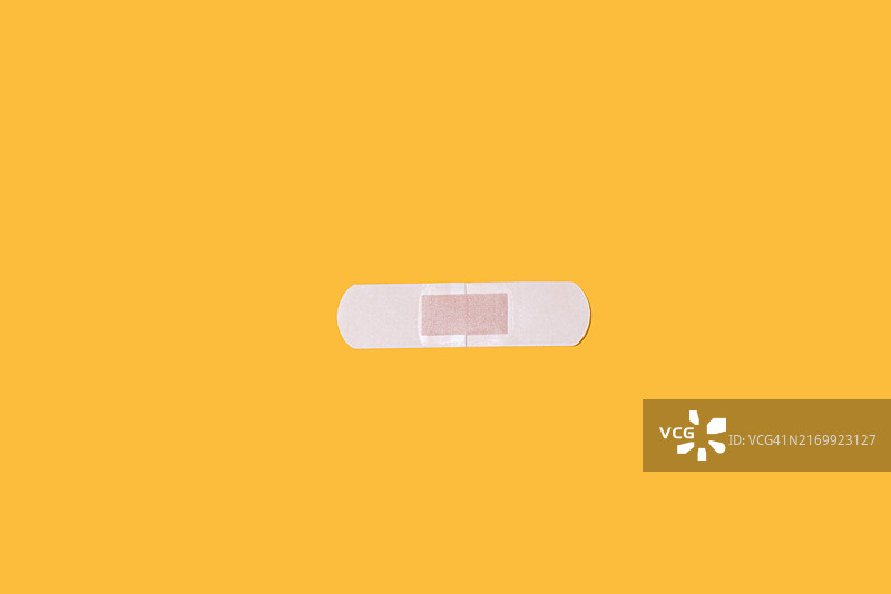 黄色背景上的创可贴：急救、身体护理、伤口图片素材