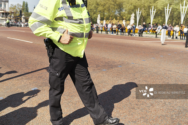 侧面视角：白天，一名男交警站在街上，背景是人群图片素材