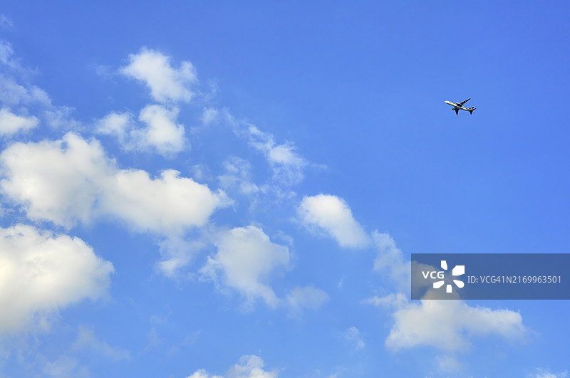 在蓝色天空的背景下，飞机穿梭于云层中图片素材