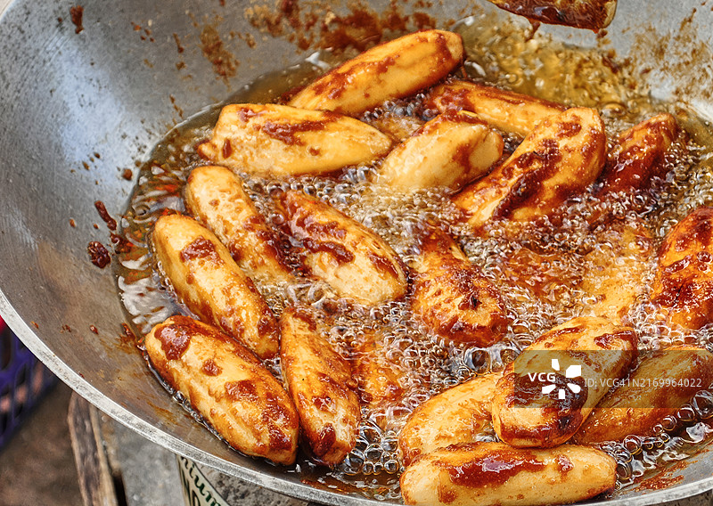裹着糖在大型炒锅中油炸的香蕉小吃图片素材
