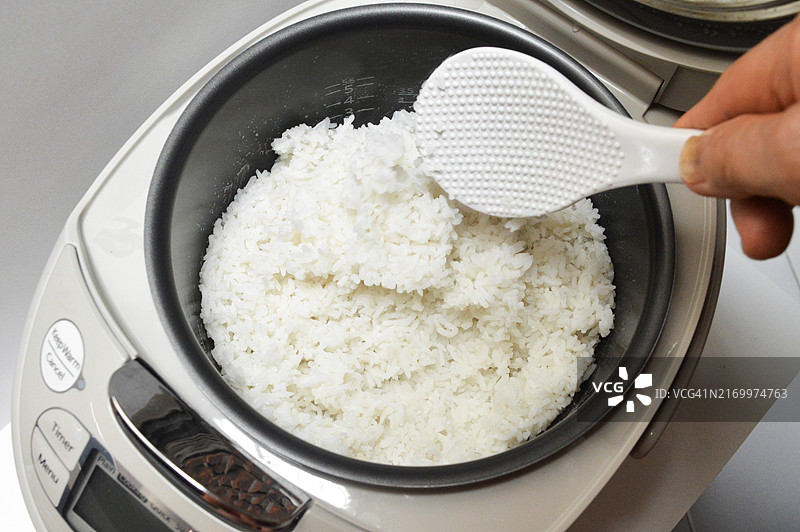 在家烹饪：在电饭煲里搅拌米饭图片素材