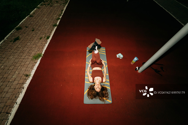 女人在房子附近的运动场训练，使用手机进行在线课程或虚拟课程图片素材