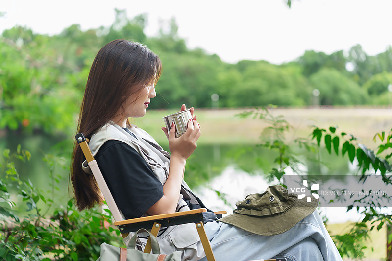徒步者坐在森林的椅子上休息，手持杯子欣赏周围环境图片素材